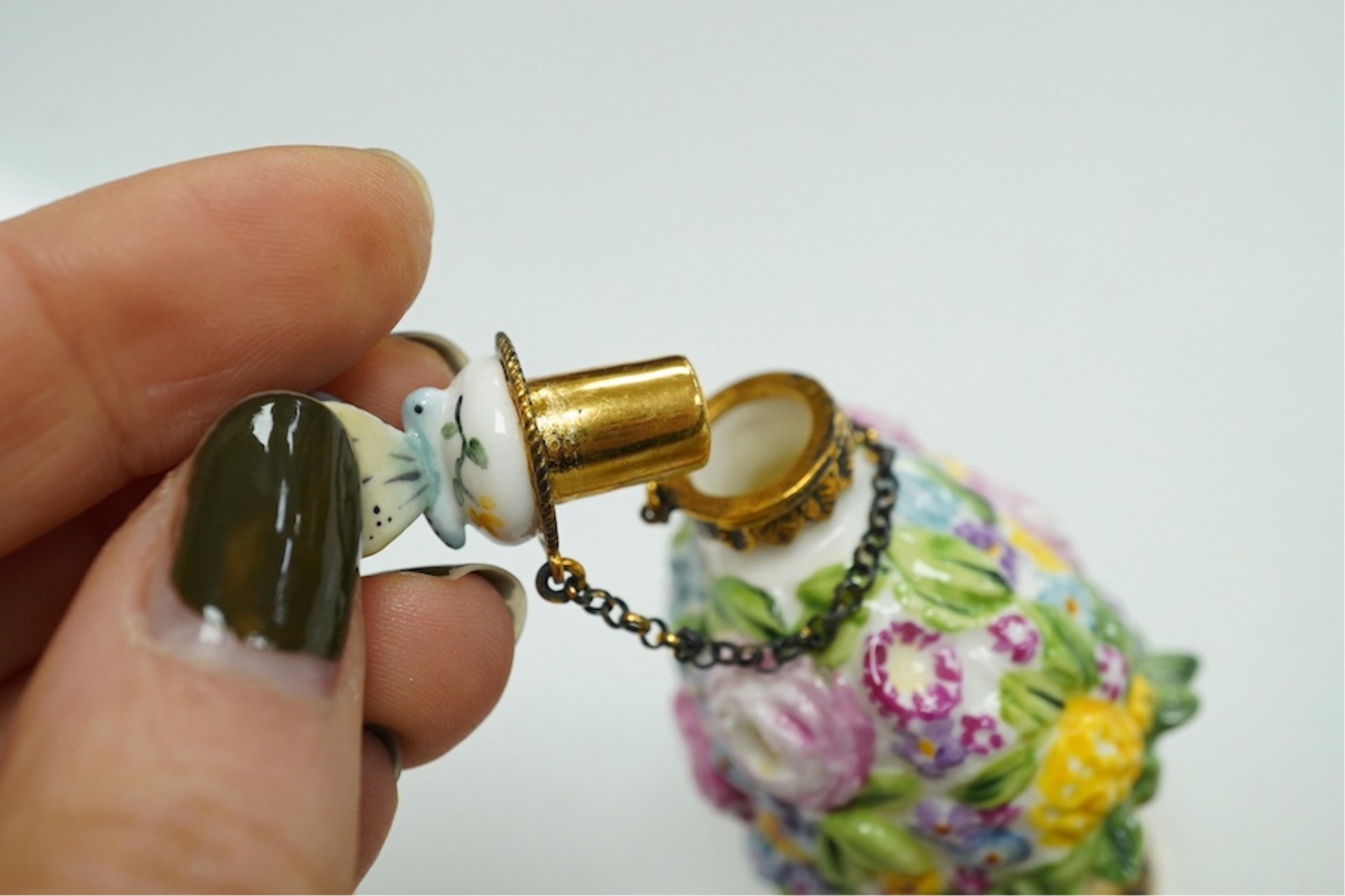 A miniature porcelain egg shaped scent bottle, on chain, two Halcyon Days scent bottles and a circular enamelled paperweight, (4). Condition - fair